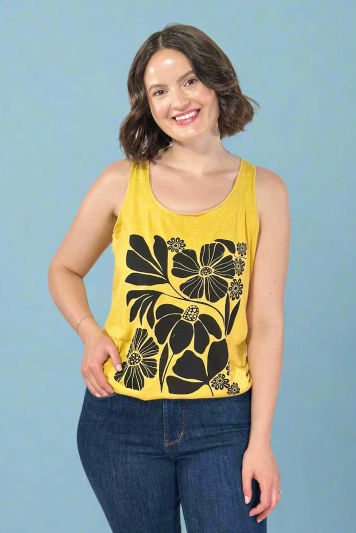 Woman wearing a yellow tank top with black floral patterns against a blue background