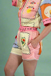 Colorful outfit with floral patterns and a pink belt on a plain background