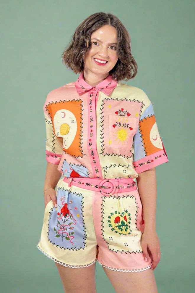 Woman wearing a colorful, patchwork-style outfit with a plain background