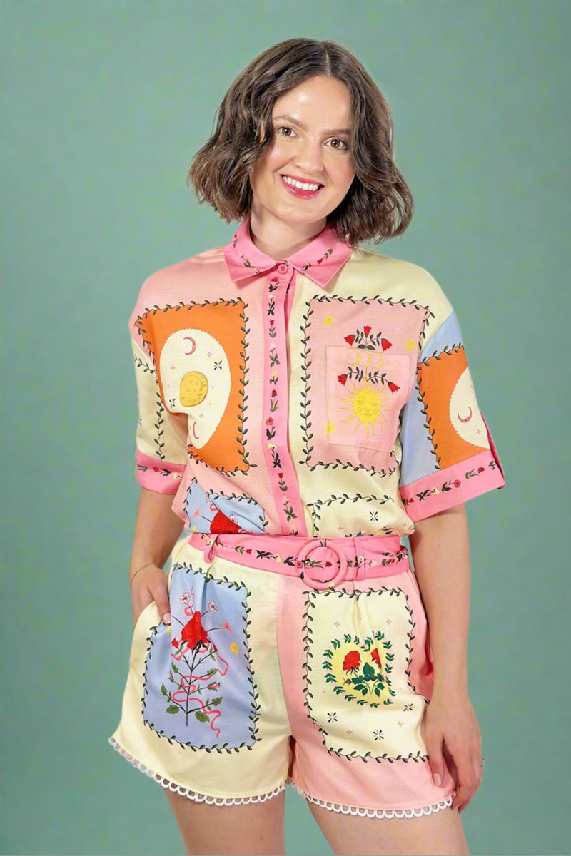 Woman wearing a colorful, patchwork-style outfit with a plain background