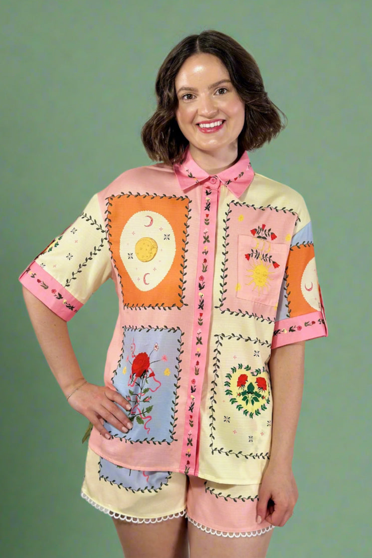 Woman wearing a colorful embroidered dress against a plain background
