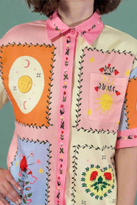 Colorful patchwork dress with embroidered patterns on a plain background