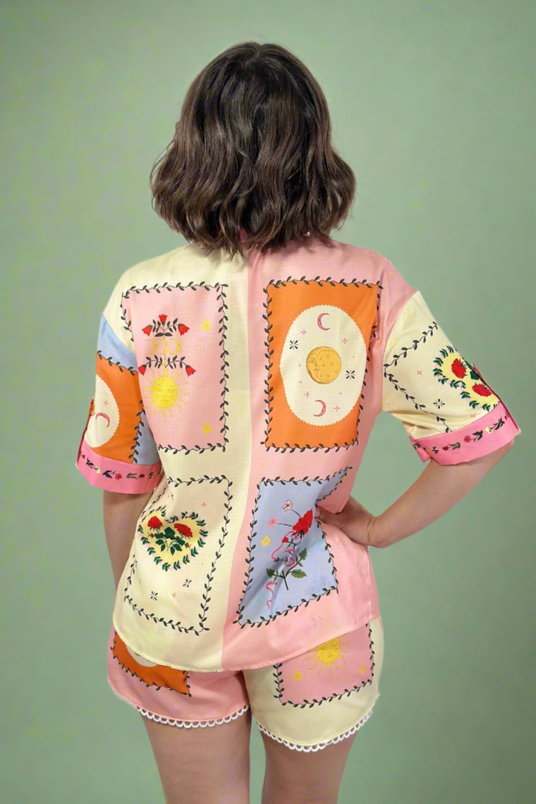 Person wearing a colorful patchwork outfit with a plain background