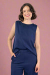 Woman wearing a navy blue sleeveless top and pants against a plain background