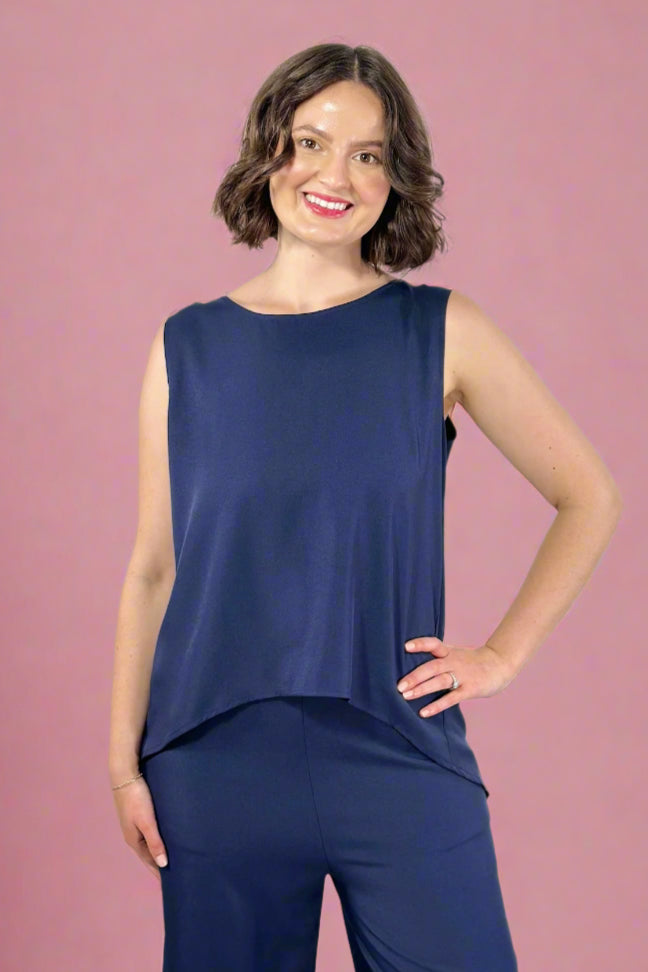 Woman wearing a navy sleeveless top and pants against a gray background