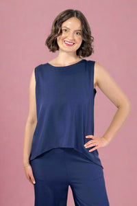 Woman wearing a navy sleeveless top and pants against a gray background