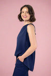 Woman wearing a navy blue sleeveless top and pants against a gray background