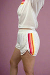 White athletic shorts with rainbow stripes on a plain background