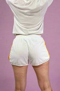 White athletic shorts with yellow accents on a plain background