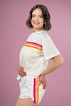 Woman wearing a white outfit with colorful stripes on a plain background