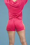 Person wearing a pink athletic outfit with shorts on a plain background