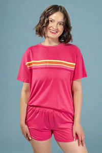 Woman wearing a pink outfit with orange stripes on a gray background
