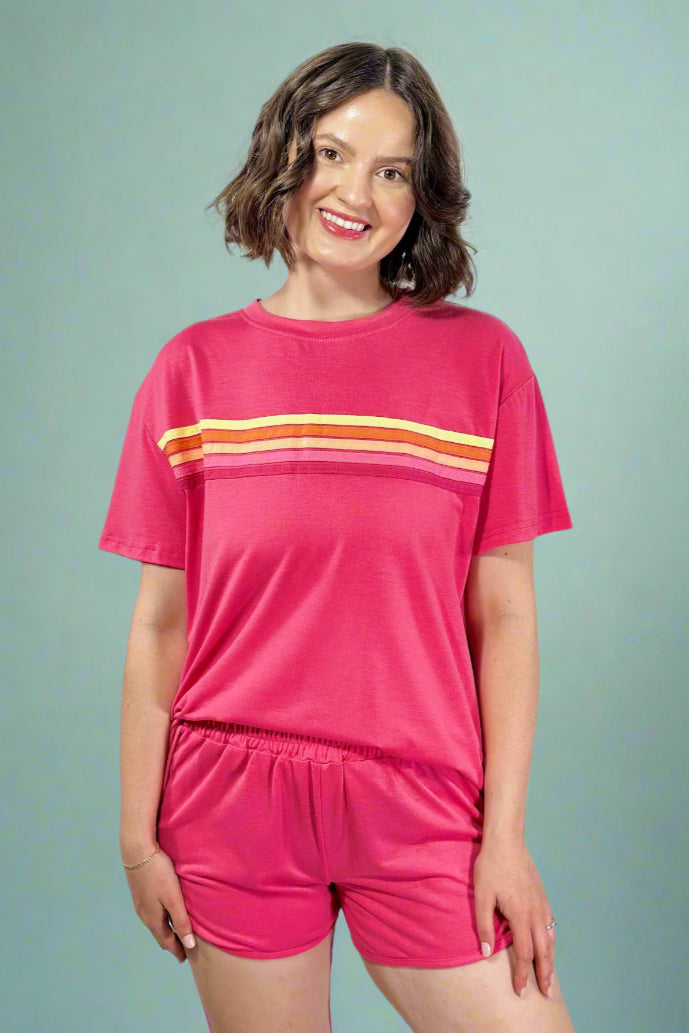Woman wearing a pink outfit with orange stripes on a gray background