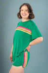 Woman wearing a green outfit with colorful stripes on a gray background