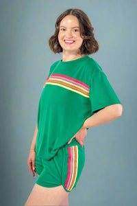 Woman wearing a green outfit with colorful stripes on a gray background