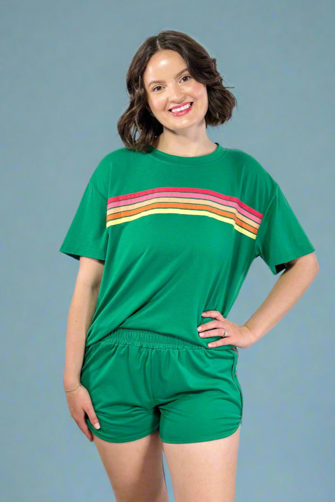 Woman wearing a green outfit with a colorful stripe on a plain background