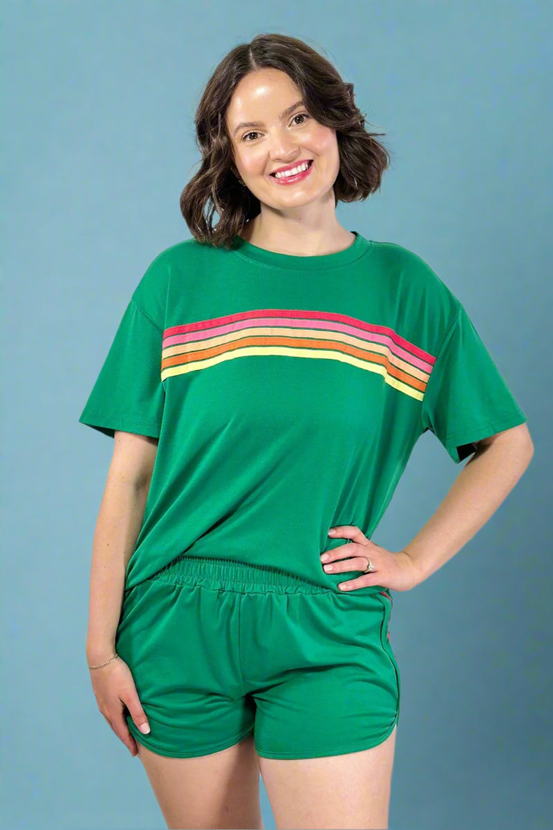 Woman wearing a green outfit with a colorful stripe on a plain background