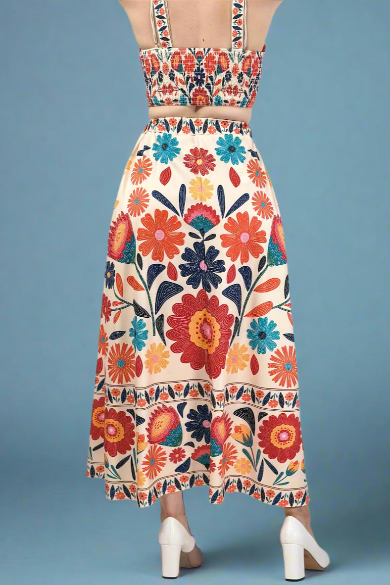 Woman wearing a short sleeve blue floral dress with elastic waist against a plain background