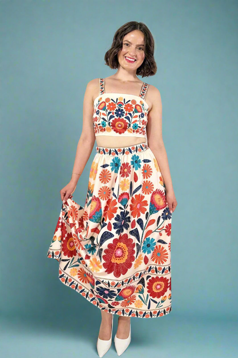 Woman wearing a colorful floral crop top and skirt set on a blue background