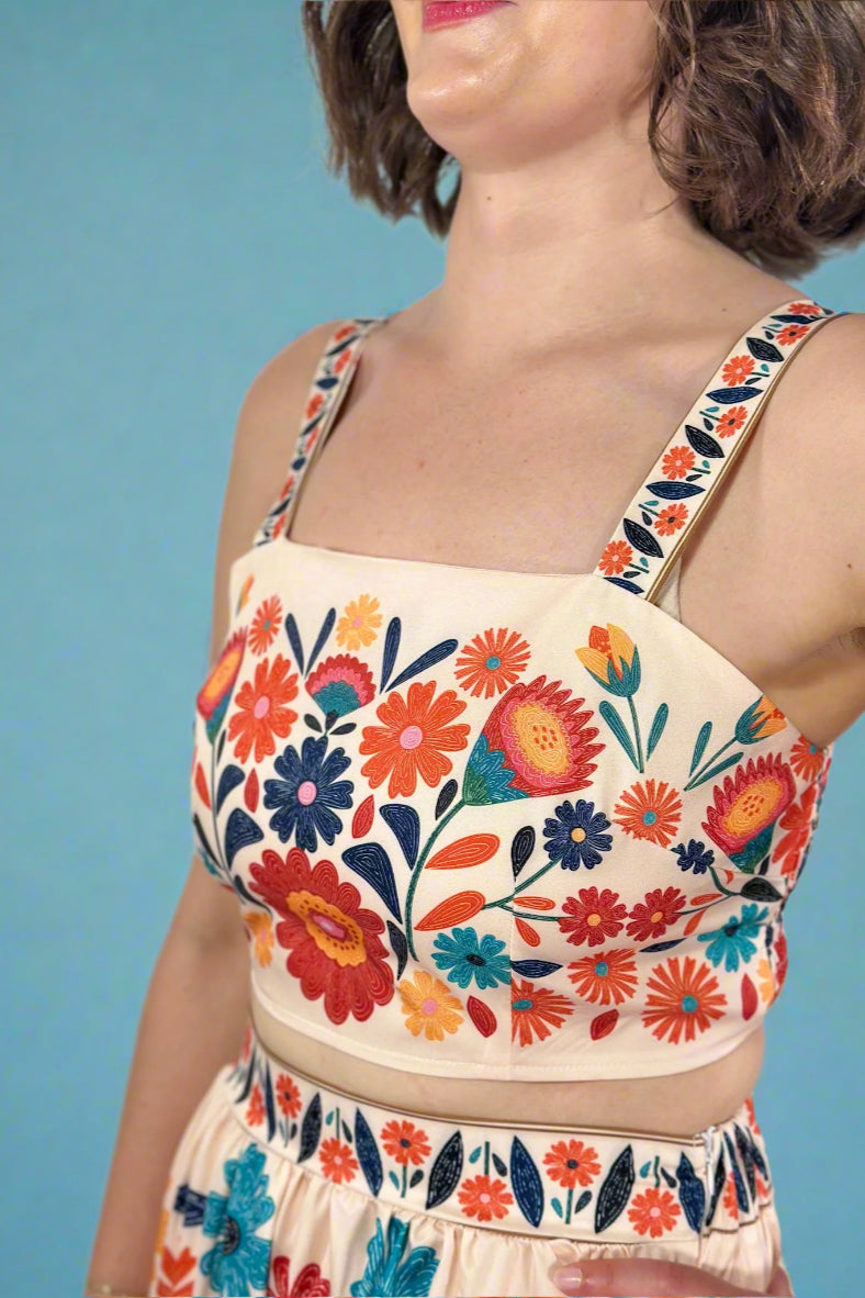 Woman wearing a colorful floral crop top and skirt set with a neutral background
