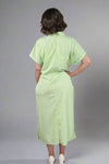 Woman wearing an oversized striped cream and light green button down midi dress with pockets. Cuffed short sleeves.