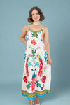 Woman wearing a colorful dress with parrot and floral patterns on a plain background