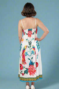 Woman wearing a floral dress with parrot design on a plain background
