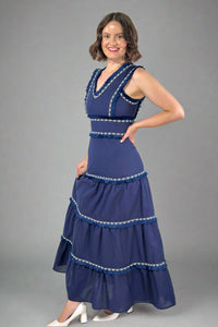 Woman wearing a blue dress with white embellishments on a white background