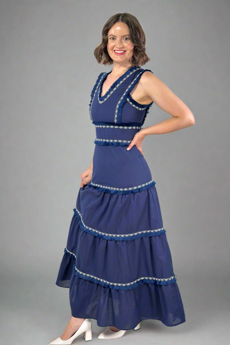 Woman wearing a blue dress with white embellishments on a white background