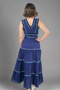 Woman wearing a blue dress with silver embellishments against a white background