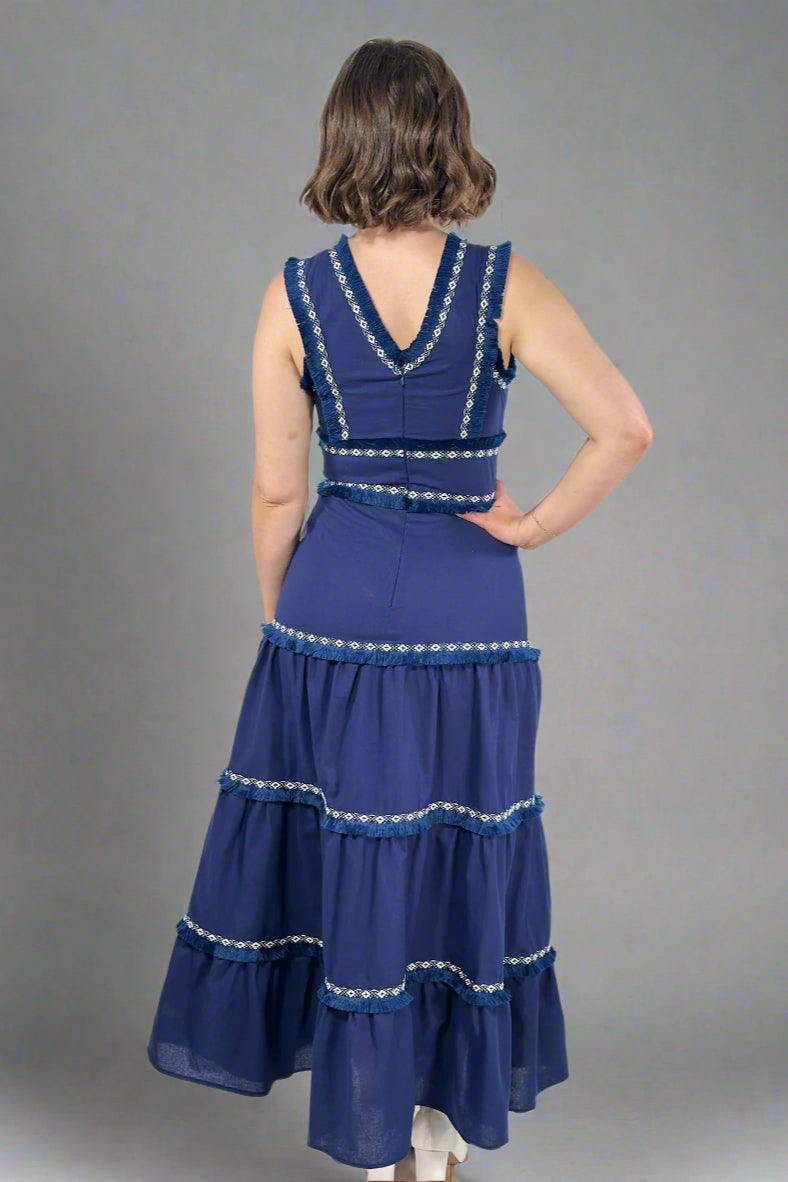 Woman wearing a blue dress with silver embellishments against a white background