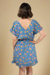 Woman wearing a blue floral dress against a plain background