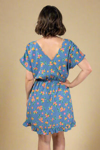 Woman wearing a blue floral dress against a plain background