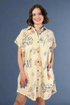 Woman wearing a beige dress with floral patterns on a plain background