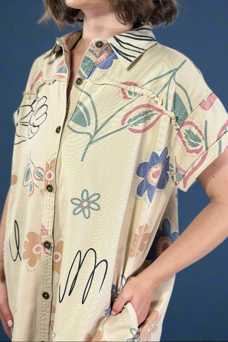 Beige shirt with floral patterns worn by a person on a plain background