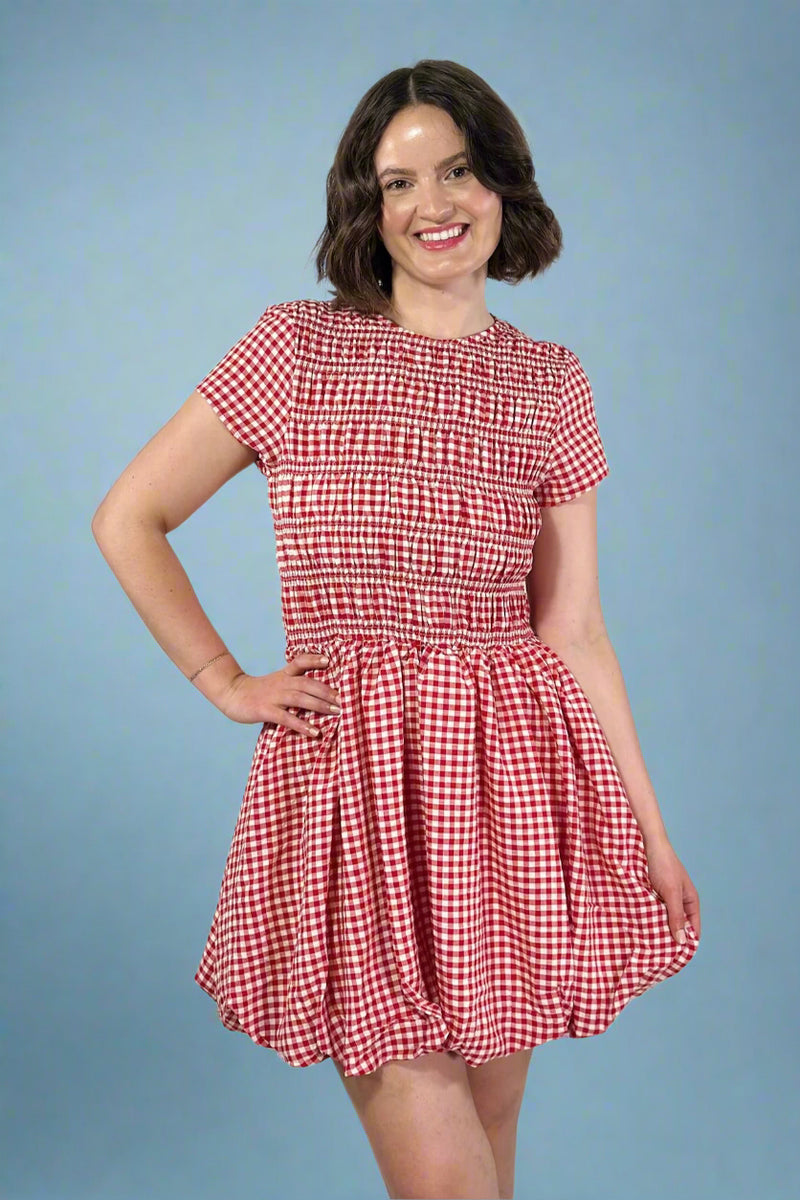 Woman wearing a red and white checkered dress against a plain background