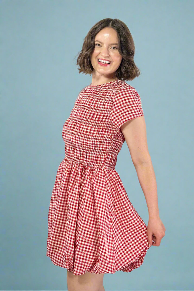 Woman wearing a red and white checkered dress against a plain background