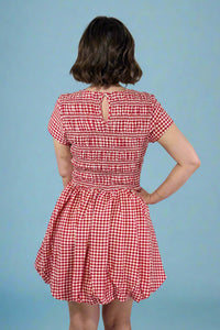 Red and white checkered dress worn by a person on a plain background