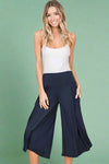 A pair of women’s lightweight navy gaucho pants falling just below the knees and featuring soft, flowy material, elastic waistband, and pockets and made in the USA.