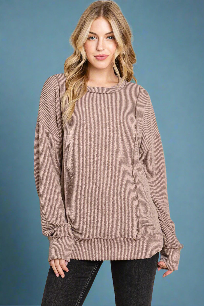 A ribbed, long sleeve top with an exposed hem. In the color mocha.