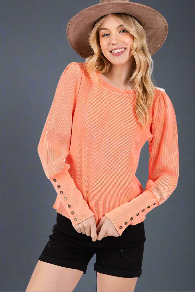 Orange mineral washed thermal waffle knit top featuring a long puff sleeve and button detailing on the cuff. 