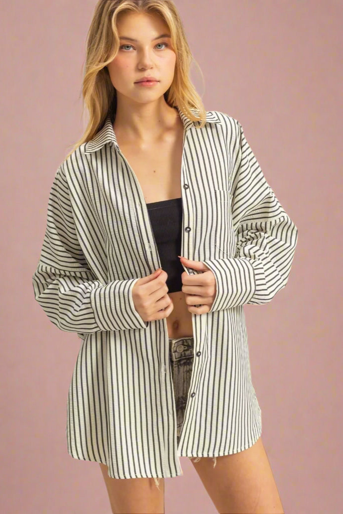 This drop shoulder, button up top features a vertical stripe pattern in black and white. It is a textured, lightweight fabric and long in length.