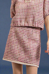 A women’s classic tweed mini skirt in berry colors with braided trim hemline.