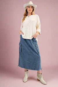 A women’s midi length, a-line, elastic waisted cargo pocket skirt in a soft faded medium wash denim.