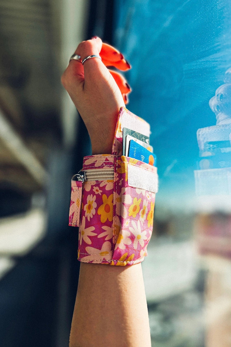 An image of a wrist wrap pouch in a pink floral pattern with Velcro closures. Made from recycled, plastic free materials.