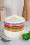 A rainbow colored, ceramic vegetable steamer for microwave.