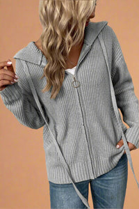 A grey zip front hooded sweater. It is ribbed, has long sleeves and is a medium weight. It has two front pockets. 