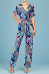A wrap style jumpsuit with a tie waist. It has short sleeves and strait legs. In a multicolor palm leaf pattern.