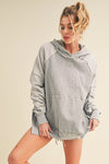A women’s oversized hooded sweatshirt featuring high side slits, front kangaroo pocket, and two toned grey color blocking.
