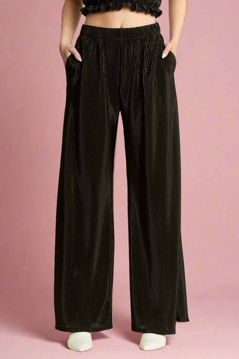Model is wearing black high waisted wide leg pants made from a shimmery black plisse fabric. 